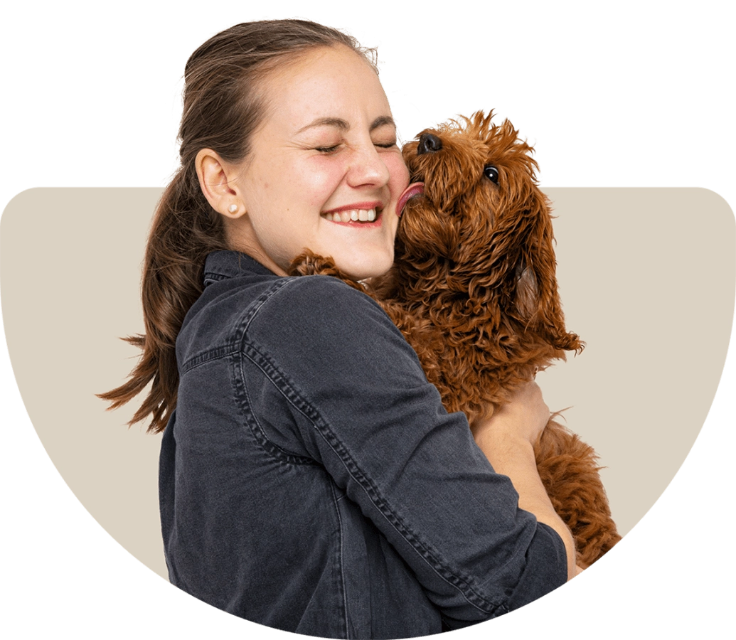 A woman hugging a curly brown dog