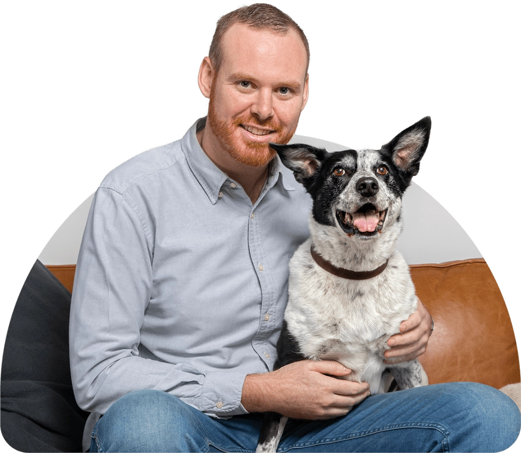 A man sitting on a couch with a black and white dog